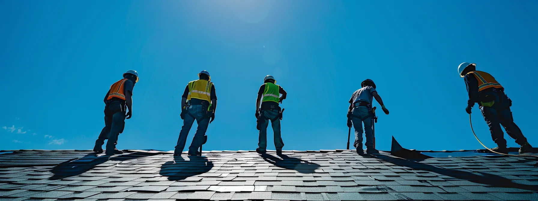 a group of emergency roofing professionals in memphis inspecting a damaged roof under a bright blue sky.